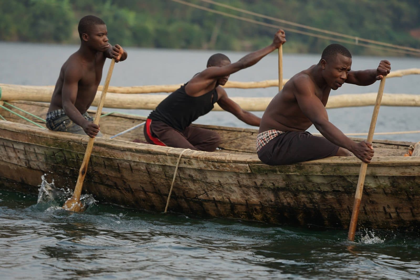 Rowers in a traditional Kivu boat, oars raised mid-stroke